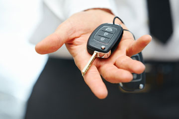Mann zeigt Kunden oder Kaufinteressenten Autoschlüssel in seiner Hand